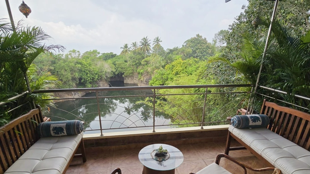 The balcony at Casa, cane sofas and a low table looking over the private freshwater lagoon and the trees