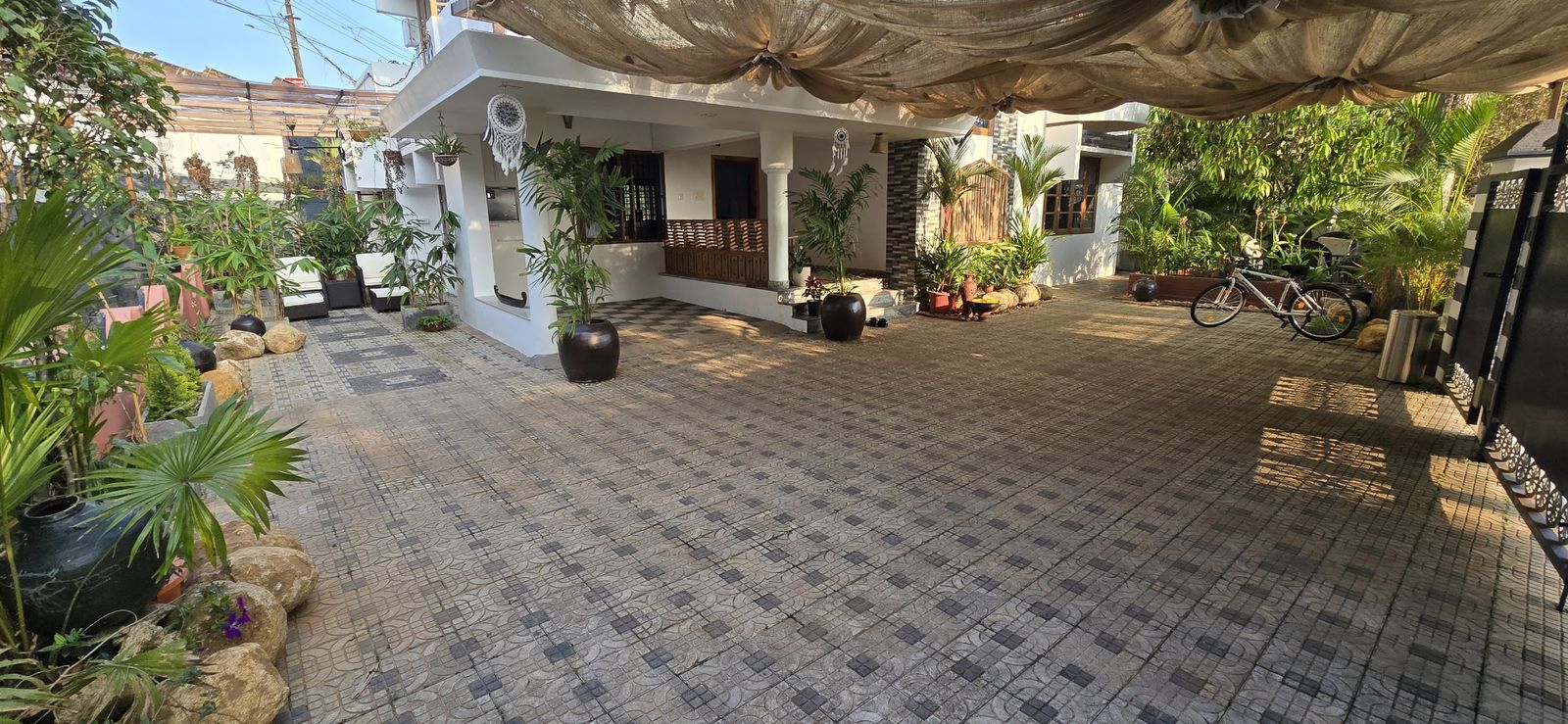 The tiled courtyard at Casa under a shade cloth, plants along the edges