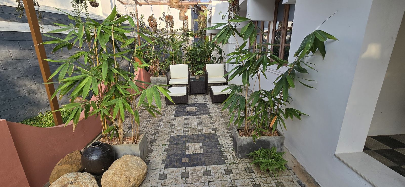 Cane chairs on the patterned tiles of the Casa garden, plants all around