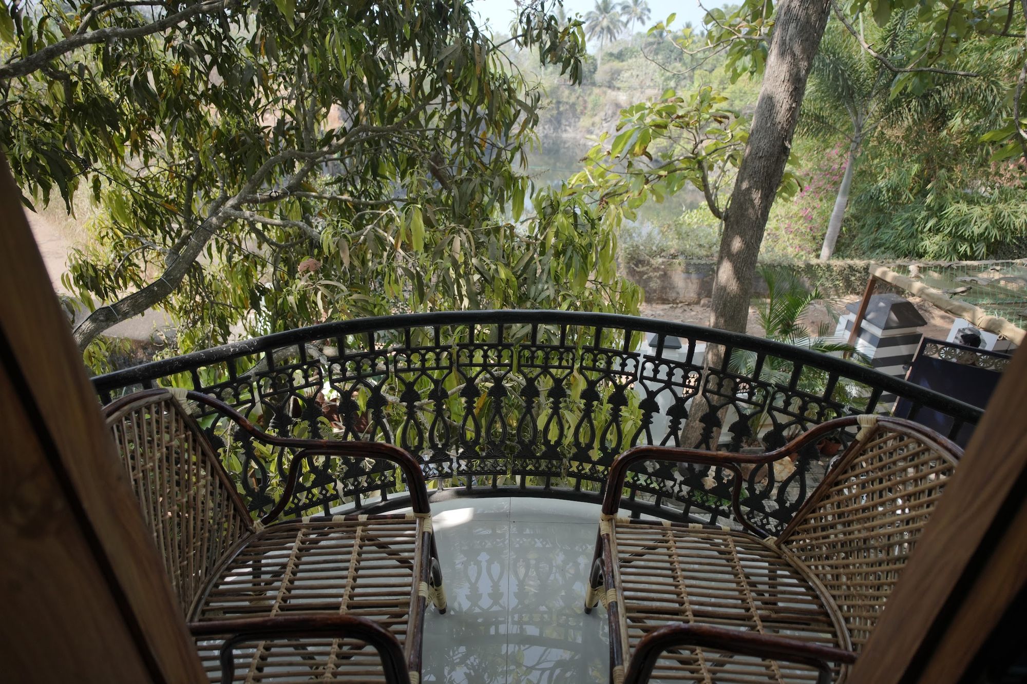 The iron balcony of La Suite Casa, cane chairs among the treetops