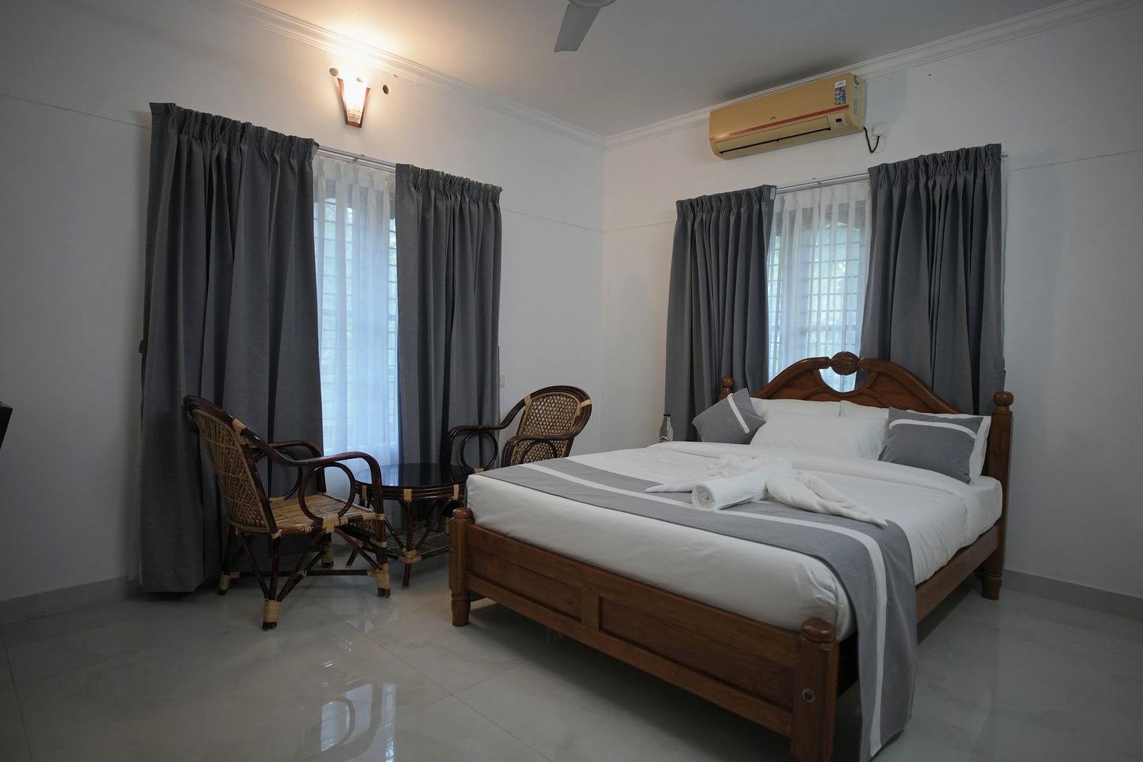 Casa Terra, a wooden double bed with cane chairs by tall curtained windows