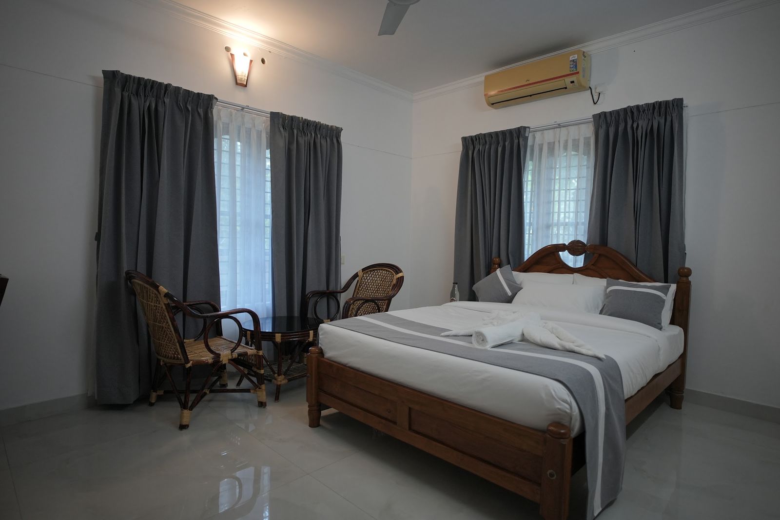 Casa Terra, a wooden double bed with cane chairs by tall curtained windows