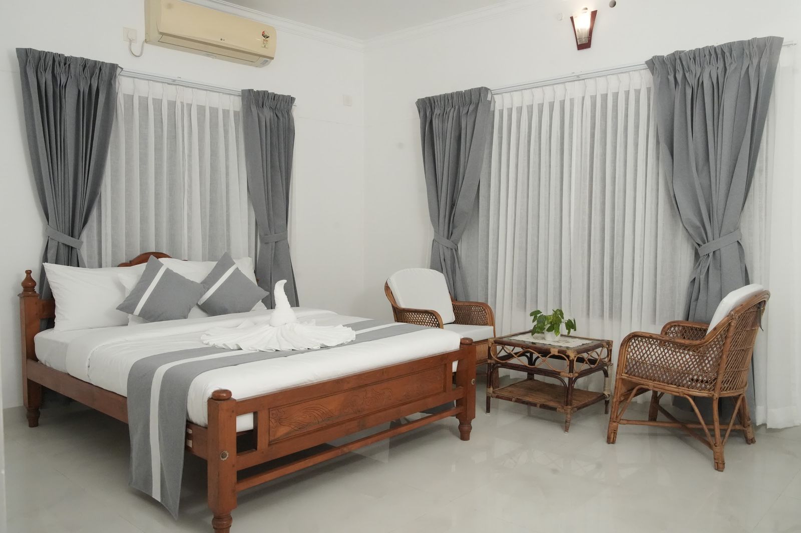 Casa Verde, a bright room with a wooden bed, cane chairs and grey curtains