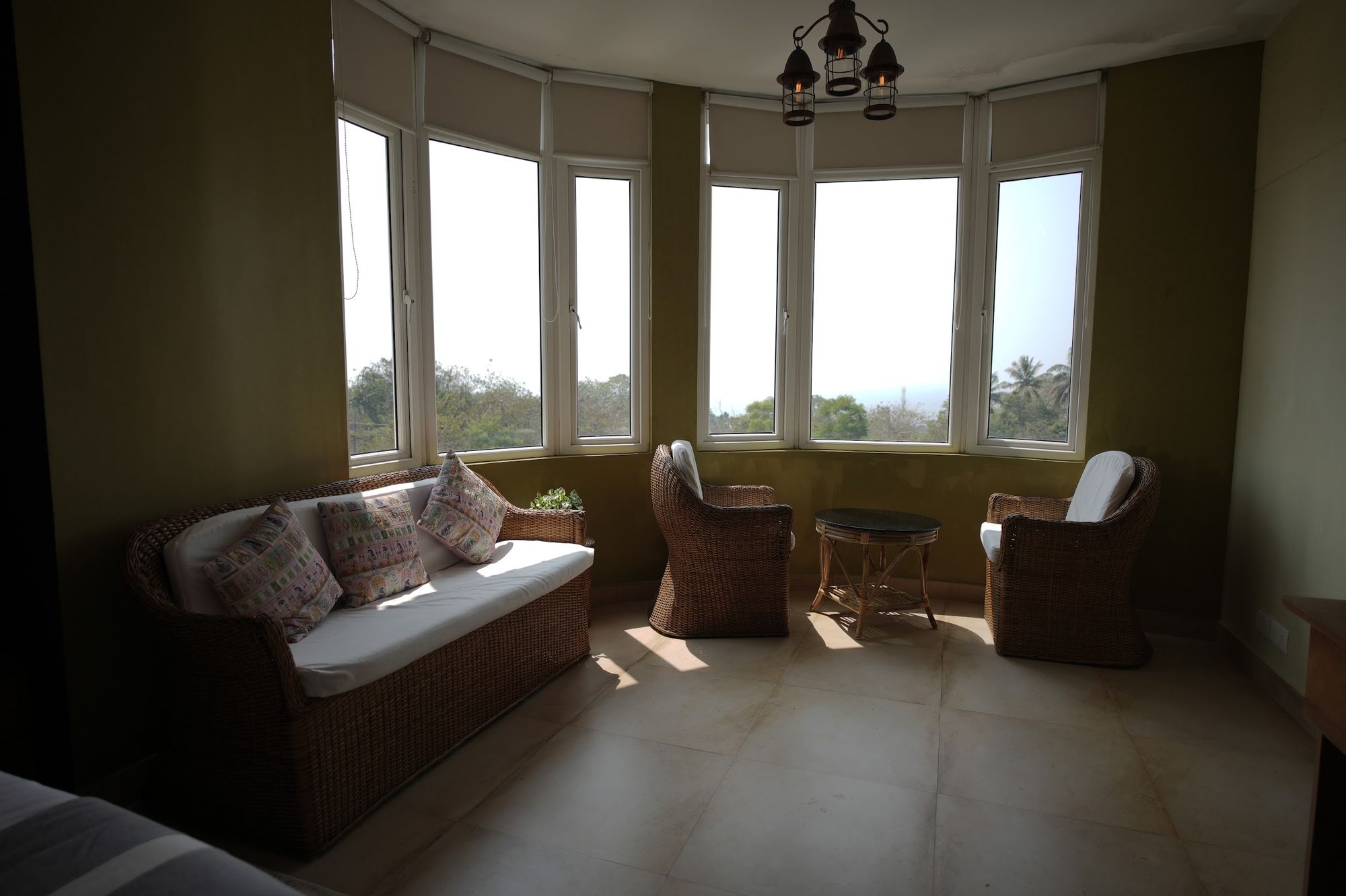 The bay window lounge of the Horizon Sky Suite at The Cove, cane sofas facing the sea light
