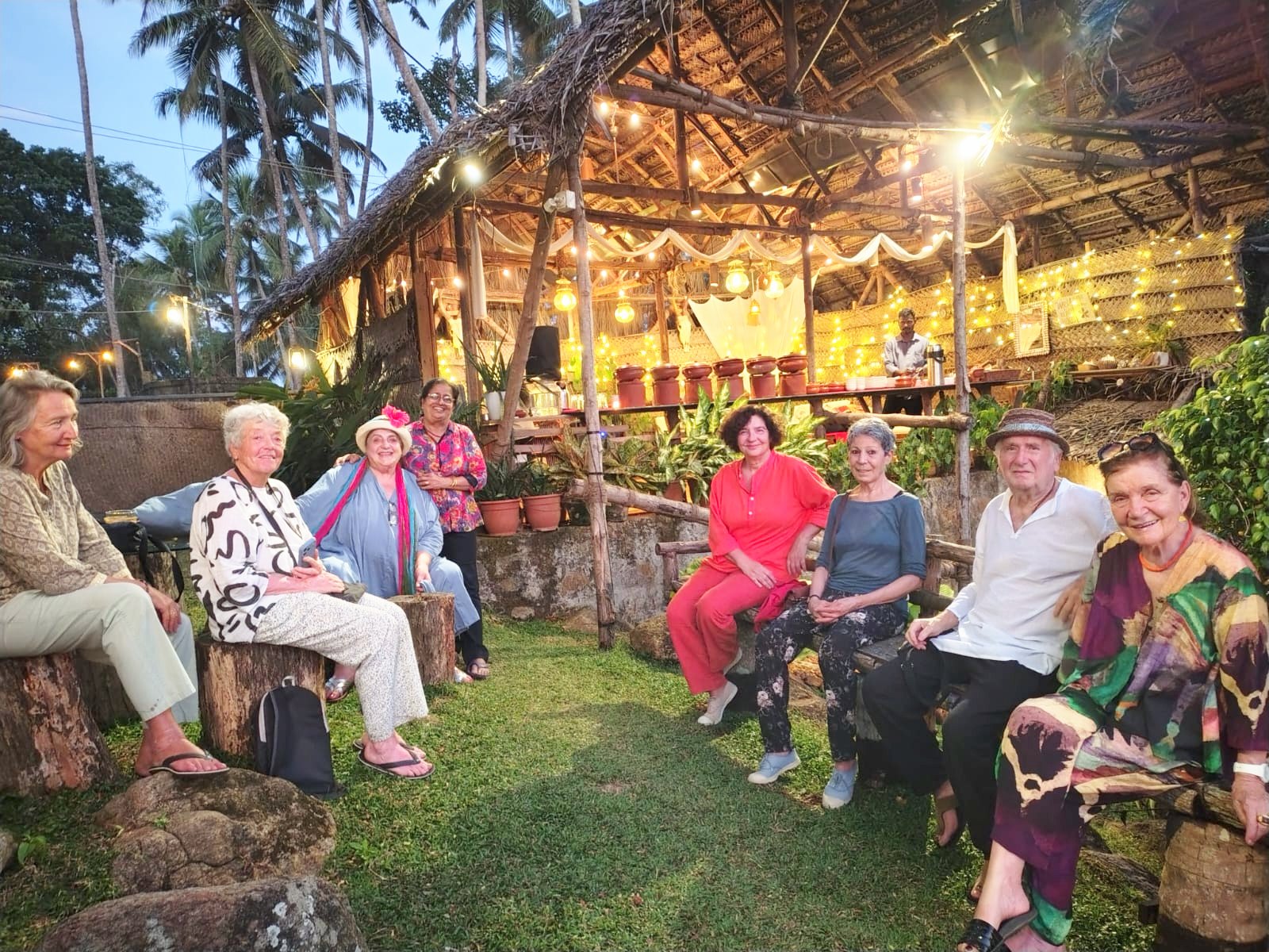 Guests seated on the lawn in front of the lit pavilion in the events garden at dusk